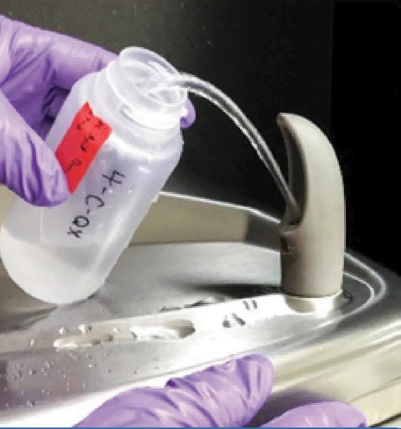 A lab technician filling a plastic testing bottle with water from aa drinking fountain.